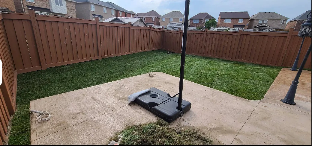Finished clean backyard with freshly installed sod and patio umbrella